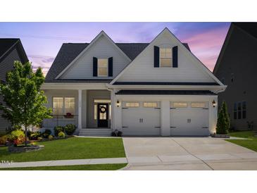 Charming home featuring a two-car garage, landscaped yard, and stylish black and white accents at 1513 Armscroft Lane, Apex, NC 27502