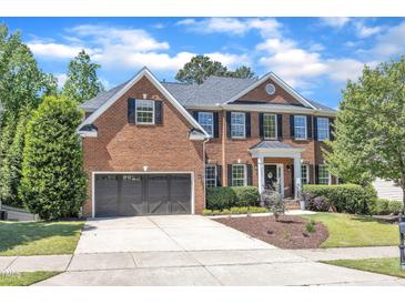 Elegant brick home featuring a two-car garage, manicured lawn, and classic black shutters at 2049 Rainy Lake St, Wake Forest, NC 27587