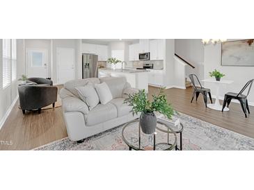 Bright living room with hardwood floors, stylish decor, and a seamless flow to the modern kitchen at 212 Brook Farm Ln, Fuquay Varina, NC 27526