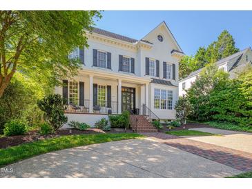 Stunning white brick two-story home with black shutters, a covered porch, and professional landscaping at 2306 Byrd St, Raleigh, NC 27608