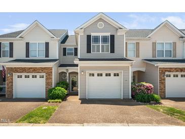 Charming townhome with a single-car garage, manicured landscaping, and neutral siding under a clear blue sky at 2609 Asher View Ct, Raleigh, NC 27606