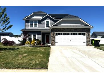 Charming two-story home with stone accents, attached two-car garage, and well-manicured lawn under clear blue skies at 267 Darecrest Ln, Wendell, NC 27591