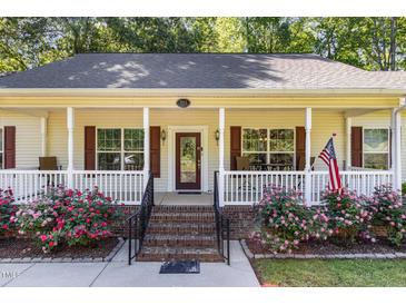 Inviting front porch with brick steps, white railing, and beautiful flowering shrubs at 2913 Escondido Farm Rd, Garner, NC 27529