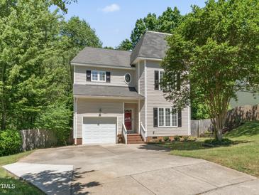 Charming two-story home with a well-manicured lawn, attached garage, and mature trees at 408 Blooming Meadows Rd, Holly Springs, NC 27540