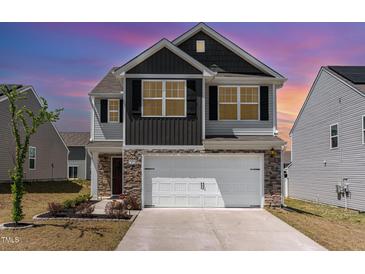 Charming two-story home with a stone and gray exterior, complemented by a well-manicured front yard and a spacious two-car garage at 729 Little Patch St, Zebulon, NC 27597