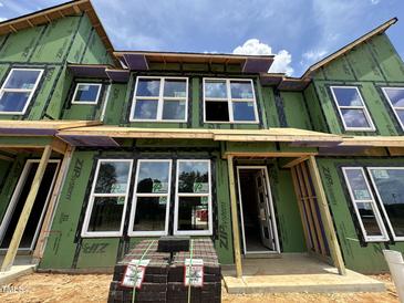 Modern townhome's exterior showcases large windows, green sheathing, and a brick pavers, offering a glimpse of contemporary living at 805 Fireship Rd, Fuquay Varina, NC 27526
