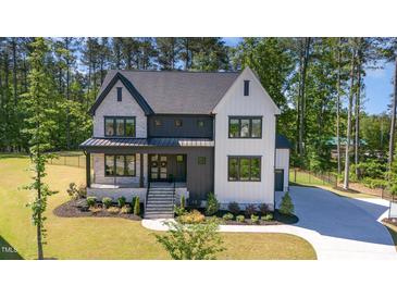 Stunning two-story home featuring a modern design, landscaped yard, and elegant entryway with stone and white plank siding at 904 Harrison Ridge Rd, Wake Forest, NC 27587