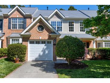 Charming townhome featuring a white garage door, brick facade, and well-maintained landscaping, creating inviting curb appeal at 9508 Vira Dr, Raleigh, NC 27617