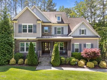 Charming home featuring stone accents, complemented by a landscaped front yard and covered entry at 1037 Lila Ln, Raleigh, NC 27614