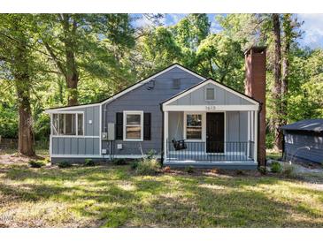 Charming home features a brick chimney and a welcoming front porch swing, perfect for enjoying peaceful afternoons at 1613 Kilmer Ter, Durham, NC 27703