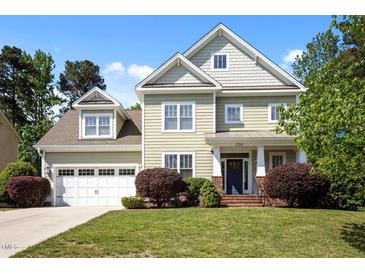Inviting two-story home with a manicured lawn, attached garage, and charming front porch at 208 Willowbend Ln, Hillsborough, NC 27278