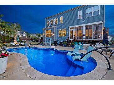Backyard pool featuring sunbathing chairs and patio, set against a two-story home at 221 Obsidian Dr, Holly Springs, NC 27540