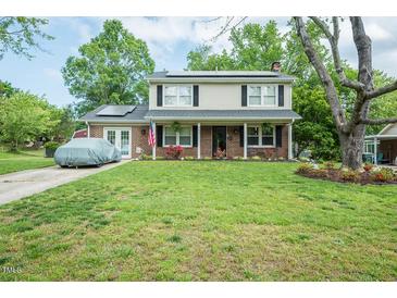 Charming two-story home with a well-manicured lawn, solar panels, and an American flag displayed at 304 Cornelia Dr, Graham, NC 27253