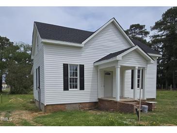 Charming two-story house features a quaint front porch, complemented by black shutters for a touch of elegance at 305 E Harnett St, Benson, NC 27504