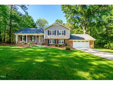 Charming brick and siding home featuring a well-manicured lawn and inviting curb appeal on a sunny day at 3301 Manor Ridge Dr, Raleigh, NC 27603