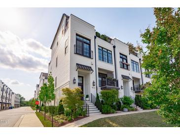 Stylish townhomes with white brick, black accents, manicured landscaping, and inviting front entrances at 411 Flat Rail Trl, Cary, NC 27511