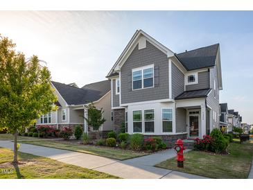Charming two-story home boasts stone accents, gray siding, a manicured lawn, and vibrant flowerbeds at 5200 Beckom St, Raleigh, NC 27616