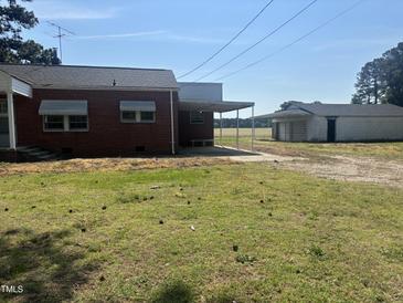 Rustic brick house with a car port near a large field and outbuildings at 6555 Nc 58, Nashville, NC 27856