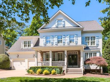 Charming two-story home with blue shutters and a covered front porch, surrounded by lush greenery at 800 Skymont Dr, Holly Springs, NC 27540