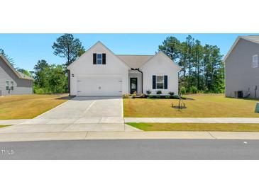Charming one-story home showcasing a manicured lawn, flower beds, and a two-car garage at 823 Biltmore Dr, Sanford, NC 27332