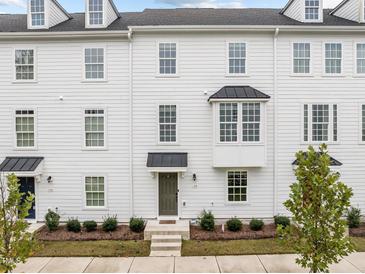 Charming townhouse featuring a light gray exterior, trimmed shrubbery, and a well-manicured lawn at 104 Vallco Ln, Durham, NC 27713