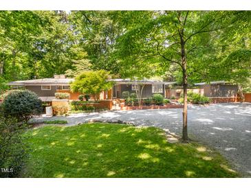 Beautiful single-story home with a well-manicured lawn and mature trees creating a private, park-like setting at 1111 Sourwood Cir, Chapel Hill, NC 27517