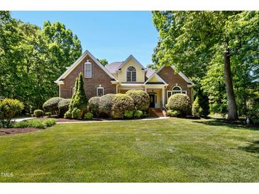 Stunning brick home featuring manicured lawn, mature trees, and attractive landscaping at 150 Georgetown Woods Dr, Youngsville, NC 27596