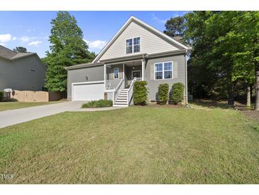 Charming two-story home with a well-manicured lawn, a garage, and stairs leading to the front porch at 20 Paddy Ln, Youngsville, NC 27596