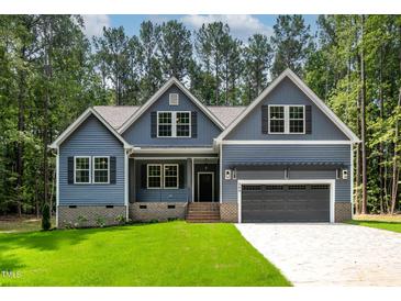 Charming home with blue siding, black shutters, a two car garage, and a well manicured green lawn at 249 Rawhide Dr, Louisburg, NC 27549