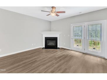 Bright living room features a cozy fireplace, ceiling fan, and access to the outdoors via french doors at 2705 Wyntercrest Ln, Durham, NC 27713