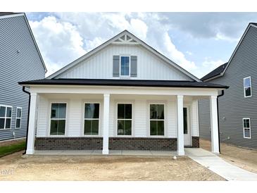 Charming new construction home featuring a stylish white exterior and inviting front porch with brick accents at 2874 Quarry Rd # 165, Rolesville, NC 27571