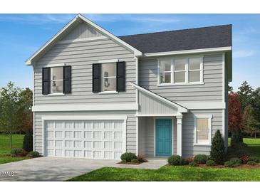 Charming two-story home showcasing light gray siding, a neatly manicured lawn, and a welcoming blue front door at 305 Spelt Ct, Rolesville, NC 27571