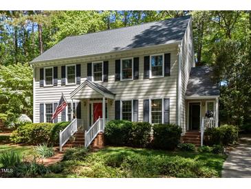 Charming two-story home featuring a red front door, black shutters, and a beautifully landscaped front yard at 404 Emerywood Dr, Raleigh, NC 27615