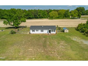 Charming home boasts new roof, white siding, and ample yard space, surrounded by lush trees at 640 Short Journey Rd, Smithfield, NC 27577