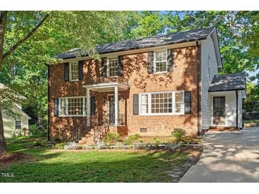Charming two-story brick home with mature trees and professionally landscaped front yard at 7213 St Ledger Dr, Raleigh, NC 27613