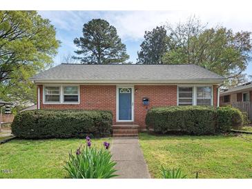 Charming brick home featuring a manicured lawn with lush shrubbery and a welcoming blue front door at 809 Leon St, Durham, NC 27704
