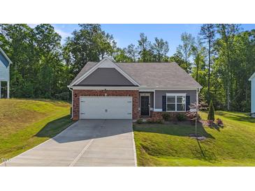 Charming single-story home featuring a brick and siding exterior, attached garage, and well-maintained landscaping at 94 Shooting Star Ln, Clayton, NC 27520