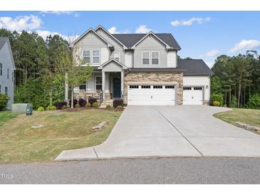 Charming two-story home with stone accents, three car garage, and a well-maintained lawn at 1309 Magnolia Gln Cir, Wake Forest, NC 27587