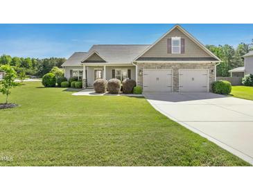 Charming home boasts a well-manicured lawn, an attached two car garage, and impeccable landscaping at 17 Kaki Ct, Selma, NC 27576
