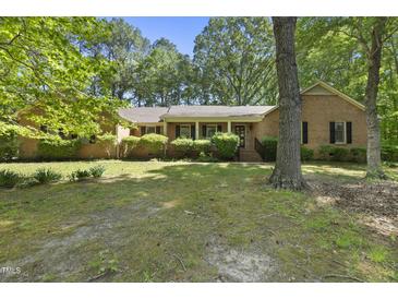 Charming single-story brick home surrounded by lush greenery and a well-maintained lawn at 2001 Lovdal Dr, Raleigh, NC 27613