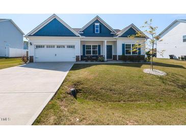 Charming single Gathering home showcasing blue and white color palette, a two car garage, and manicured front lawn at 218 E Tecoma Ln, Clayton, NC 27520