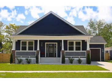 Charming navy home featuring a covered porch, white trim, and well-manicured landscaping at 305 W Waddell St, Selma, NC 27576