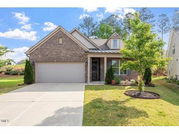Charming brick home featuring an attached garage and a beautifully landscaped front yard with lush green grass at 52 Brunello Ct, Clayton, NC 27527