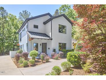 Charming renovated two-story home with white brick, black trim, manicured landscaping, and covered front porch at 631 Linfield Dr, Durham, NC 27701
