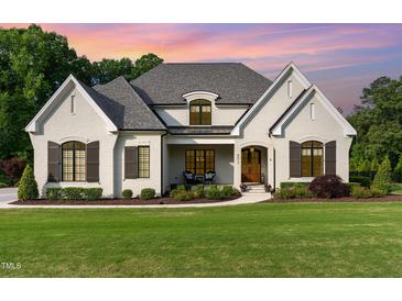 Charming two-story white brick home featuring manicured landscaping and a welcoming front porch at 8017 Discovery Falls Trl, Wake Forest, NC 27587
