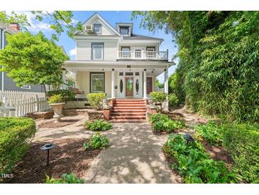 Inviting two-story home with charming curb appeal, lush landscaping, brick pathway and grand entrance with porch at 1000 Lamond Ave, Durham, NC 27701
