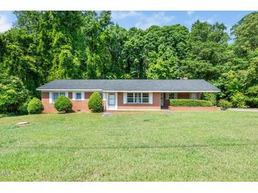 Charming single-story brick home featuring a well-manicured lawn and mature trees at 1041 Davis Dr, Apex, NC 27523