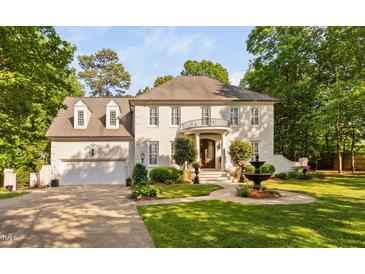 Stunning white brick home featuring a circular balcony, water fountain, lush landscaping and a three-car garage at 106 Clendenen Ct, Cary, NC 27513