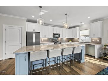 Bright kitchen features a large island with seating, granite countertops and stainless steel appliances at 110 Deacon Ridge Ln, Youngsville, NC 27596