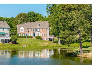 Stunning brick home with lush lawn, surrounded by trees and a serene lake view at 12527 Bellstone Ln, Raleigh, NC 27614